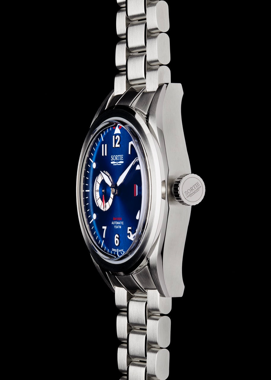 Silver stainless steel watch with a blue dial, white numerals and red colour accents. Includes a seconds hand dial and date display. Watch it shown from the side.