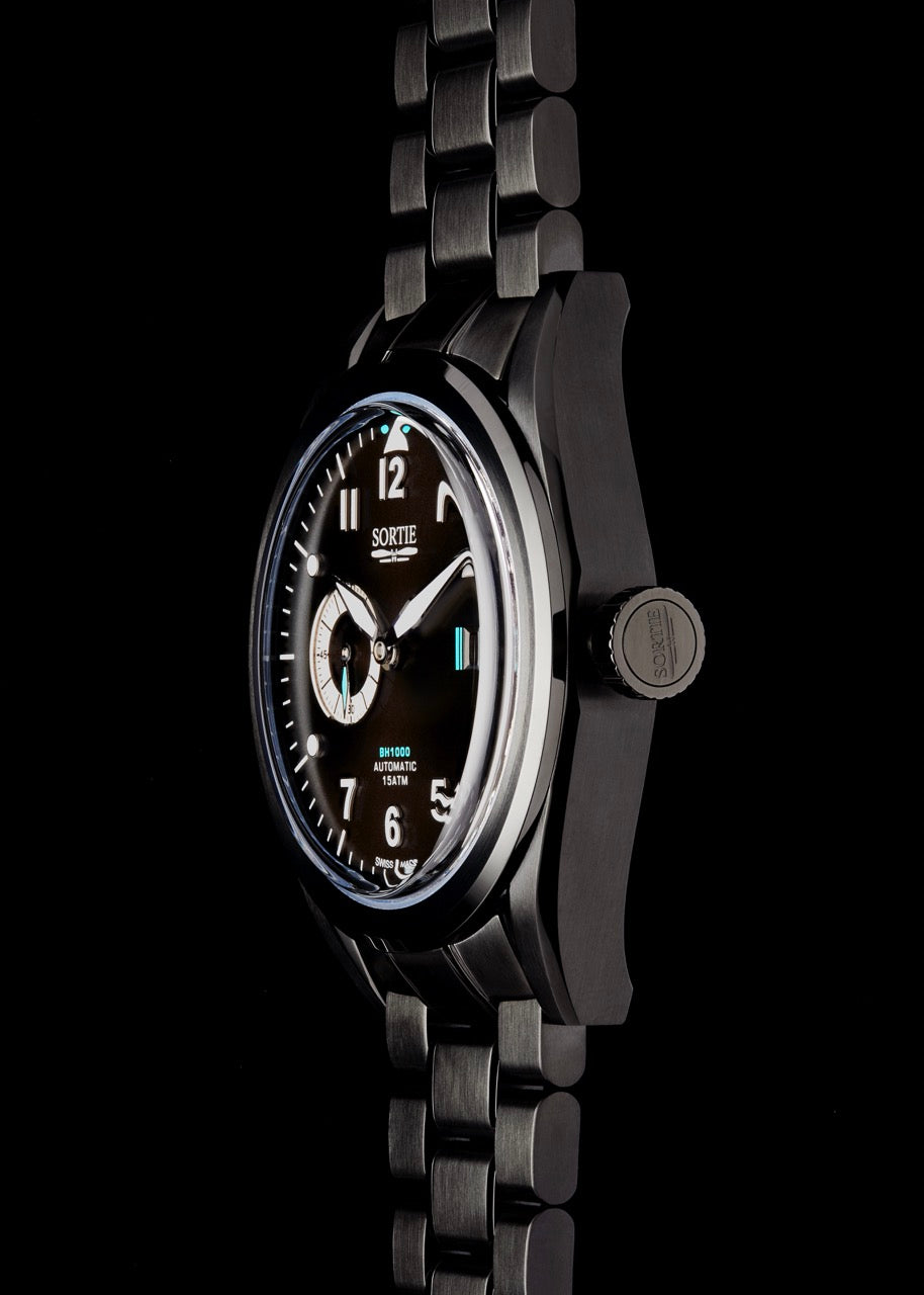 Black watch with a black dial, white numerals and blue colour accents. Includes a seconds hand dial and date display. Watch is shown from the side.