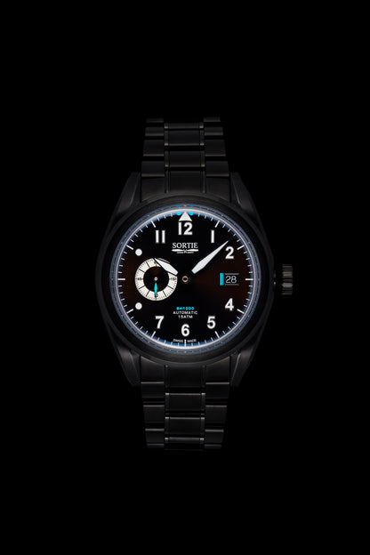 Black watch with a black dial, white numerals and blue colour accents. Includes a seconds hand dial and date display. Watch is shown face-on.