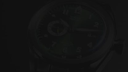 A video showing a silver stainless steel watch with a green dial, white numerals and yellow colour accents. Includes a seconds hand dial and date display. The video shows close ups of the watch at different angles.